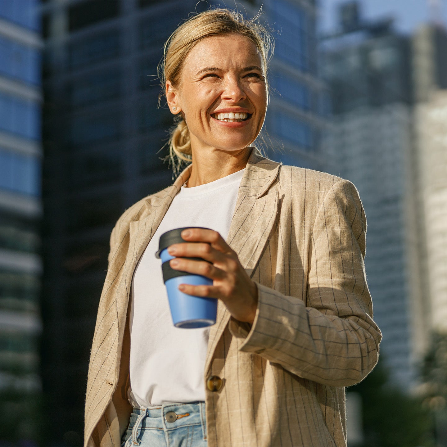 Donna sorridente che beve da una tazza gialla alla luce del mattino, piena di energia e stabilità.
